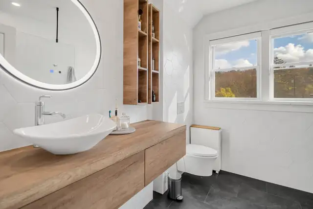 Fall Creek, Ithaca bathroom with a floating wood vanity, vessel sink and round lighted mirror