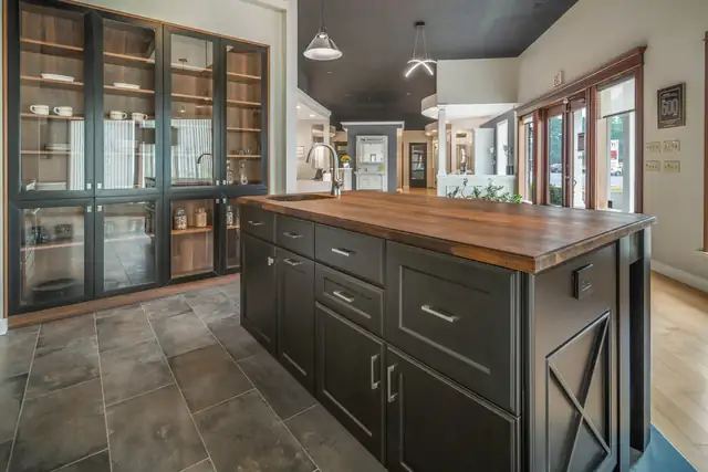 Freeville, NY kitchen with a dark painted island, a walnut butcher block top, glass-front cabinets and a slate tile floor