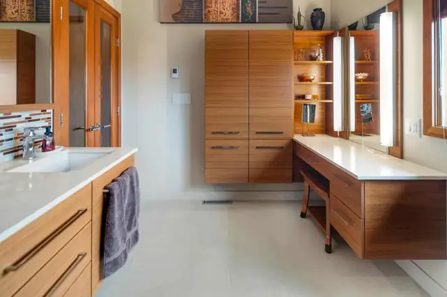 Remodeled bathroom in an Ithaca, NY home with a warm wood vanity, lighted mirror cabinet and built-in linen storage
