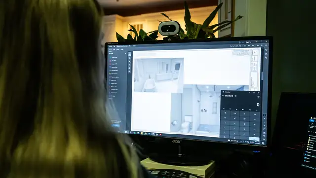 Upscale Remodeling designer working on a bathroom plan and costs at a computer