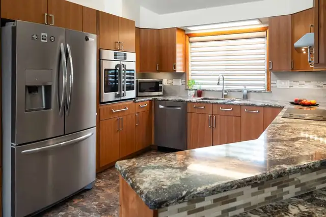 Remodeled kitchen in an Ithaca, NY home with wood cabinets, granite counters, glass tile backsplash and stainless appliances