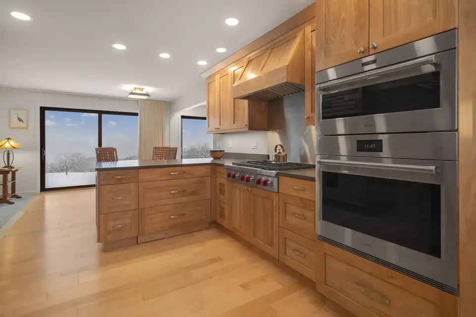 Kitchen remodeling Ithaca NY: home addition kitchen with warm wood cabinets, stainless double wall ovens and a sliding door to the yard